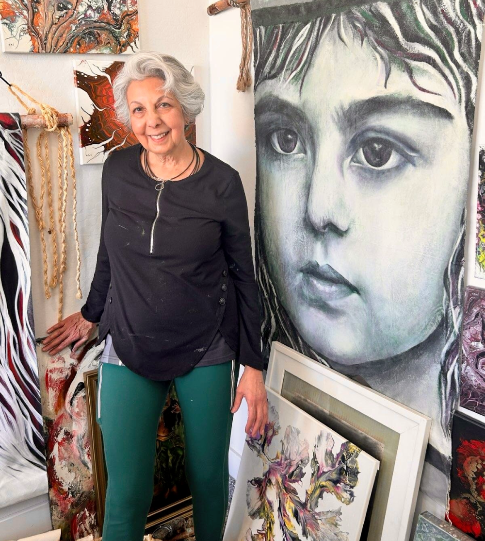 Woman standing beside large portrait painting.